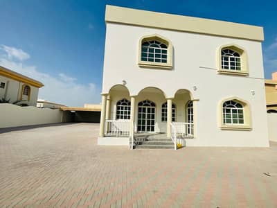 For rent, a two-storey villa on an asphalt street in Ajman, Al Rawda 1 area, excellent location, with air conditioning  5 rooms, a hall, a sitting room, and more 7 bathrooms with a maid's room The land area is 10 thousand square feet It is close to all se