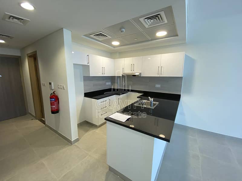 7 soho-square-saadiyat-open-kitchen-with-marble-counter-top-and-wooden-storage-spaces-and-exhaust-fan. jpg