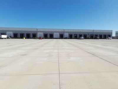 Industrial Land for Sale in Industrial Area, Umm Al Quwain - An_empty_industrial_plot_with_a_large_concrete_surface_featuring_several_large_loading_docks_and_warehouse_buildings_in_the_background. _The_sky_is_clear_and_blue_and_there_are_no_vehicles_or_equipment_in_sight. _The_s. jpeg Industrial Land for Sale in Industrial Area, Umm Al Quwain - An_empty_industrial_plot_with_a_large_concrete_surface_featuring_several_large_loading_docks_and_warehouse_buildings_in_the_background. _The_sky_is_clear_and_blue_and_there_are_no_vehicles_or_equipment_in_sight. _The_s. jpeg