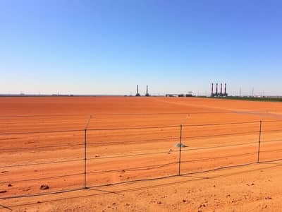 ارض صناعية  للبيع في صناعية الصجعة، الشارقة - An_expansive_empty_industrial_plot_with_dry_flat_land_stretching_under_a_sunny_sky. _The_earth_is_a_reddish_brown_color_and_the_area_is_completely_devoid_of_any_buildings_or_vegetation. _A_neat_wire_fence_encloses_the_. jpeg