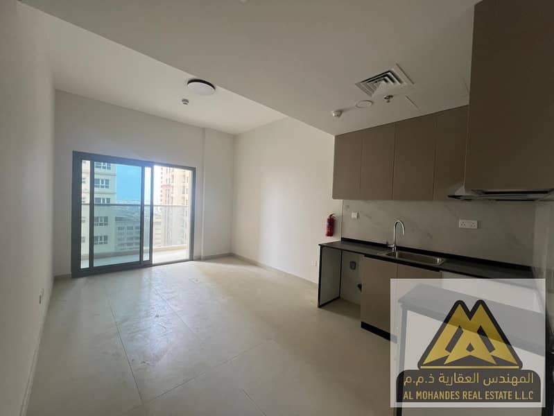 Studio apartment for annual rent in Al Aamra Residence Towers, Ajman. Spacious area with balcony, kitchen, and open view.