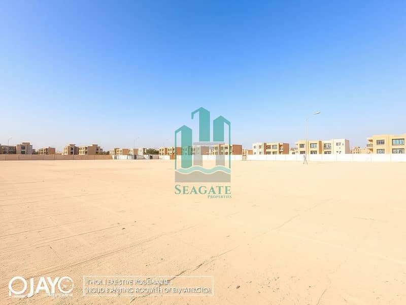 2 A_large_empty_residential_plot_in_the_UAE_situated_one_block_from_a_road. _The_scene_features_an_expansive_flat_sandy_terrain_without_trees_or_signs_creating_an_open_unobstructed_view. _The_sky_is_bright_blue_typic (2). jpeg