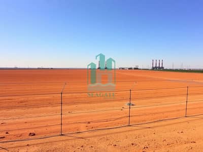 Industrial Land for Sale in Al Sajaa Industrial, Sharjah - An_expansive_empty_industrial_plot_with_dry_flat_land_stretching_under_a_sunny_sky. _The_earth_is_a_reddish_brown_color_and_the_area_is_completely_devoid_of_any_buildings_or_vegetation. _A_neat_wire_fence_encloses_the_. jpeg