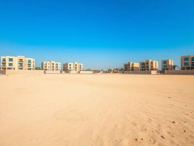 Mixed Use Land for Sale in Al Rawda, Ajman - A_large_empty_residential_plot_in_the_UAE_situated_one_block_from_a_road. _The_scene_features_an_expansive_flat_sandy_terrain_without_trees_or_signs_creating_an_open_unobstructed_view. _The_sky_is_bright_blue_typic (3). jpeg