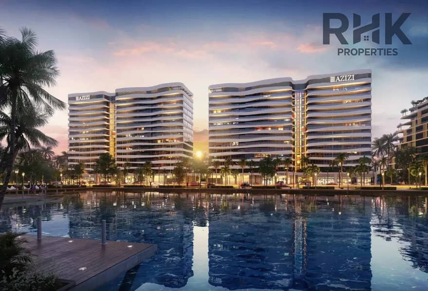8 Azizi Venice twin residential towers at sunset reflected in the lagoon