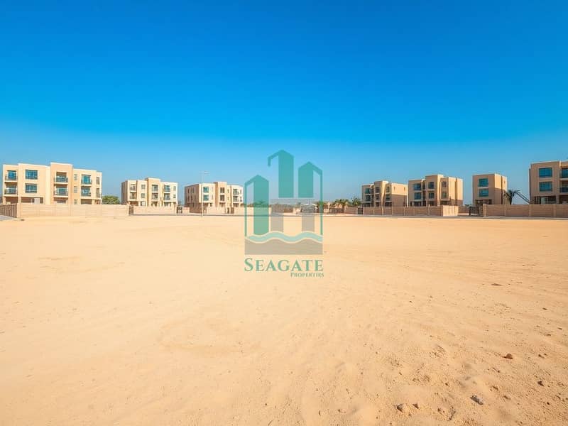 2 A_large_empty_residential_plot_in_the_UAE_situated_one_block_from_a_road. _The_scene_features_an_expansive_flat_sandy_terrain_without_trees_or_signs_creating_an_open_unobstructed_view. _The_sky_is_bright_blue_typic (3). jpeg