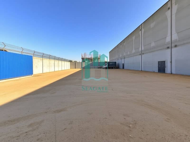 2 A_spacious_industrial_yard_similar_to_the_one_shown_with_a_large_empty_area_of_bare_ground_that_has_been_slightly_expanded. _Surrounding_the_yard_there_are_tall_sturdy_concrete_walls_for_security_with_a_blue_corrugate. jpeg