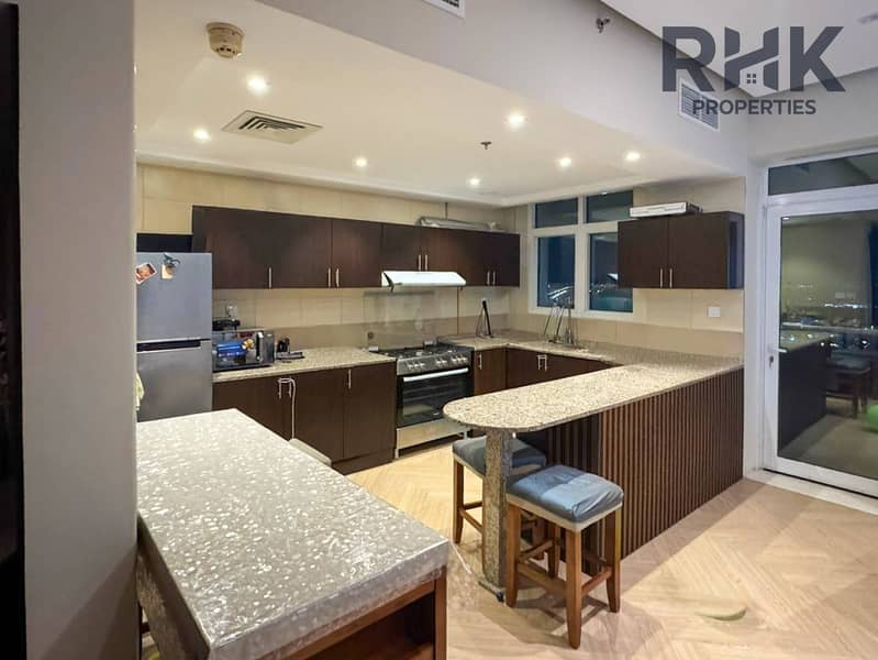 5 Open-plan kitchen with dark wood cabinets, granite counters and gas cooker in Dubai apartment