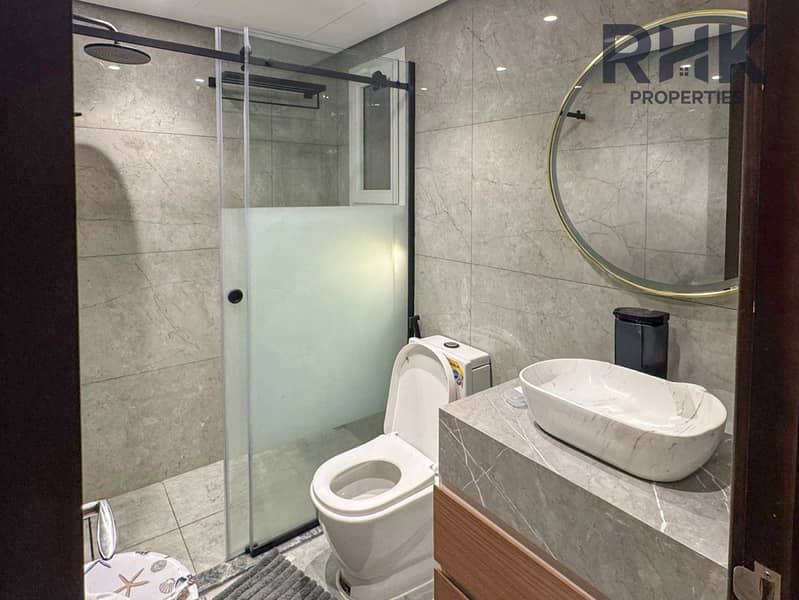 10 En-suite bathroom with rain shower, grey marble walls and gold-framed mirror in Dubai apartment