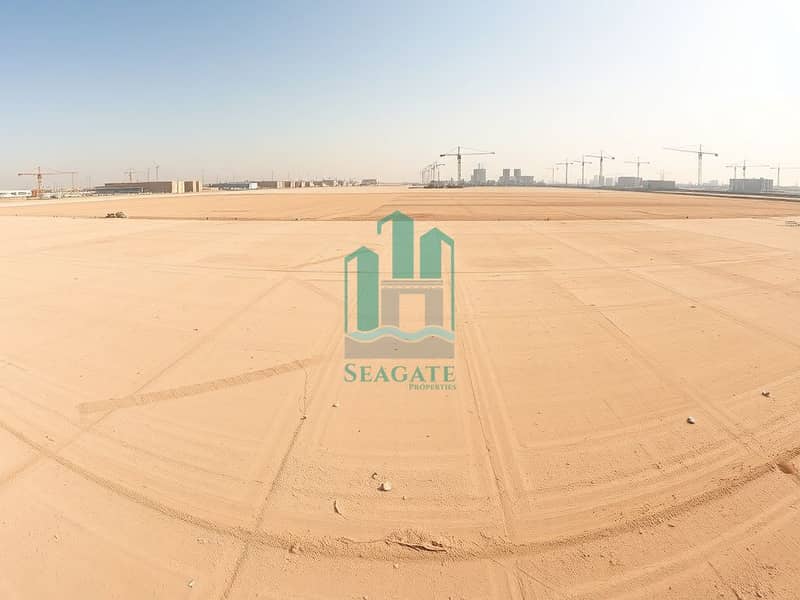 A_panoramic_view_of_an_empty_industrial_lot_in_the_UAE_showcasing_a_vast_flat_landscape_marked_for_future_development. _The_ground_is_sandy_and_dry_with_faint_markings_indicating_plot_boundaries. _In_the_distance_there. jpeg A_panoramic_view_of_an_empty_industrial_lot_in_the_UAE_showcasing_a_vast_flat_landscape_marked_for_future_development. _The_ground_is_sandy_and_dry_with_faint_markings_indicating_plot_boundaries. _In_the_distance_there. jpeg