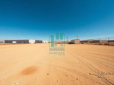 Industrial Land zum zum Verkauf in Emirates Industrial City, Sharjah - A_very_large_empty_industrial_yard_warehouse_lot_big_open_space_ground_level_wide_angle_photo_style. _Photorealistic_35mm_ultra_wide_composition_with_lots_of_negative_space_dusty_beige_gravel_dirt_surface_with_scatter. jpeg