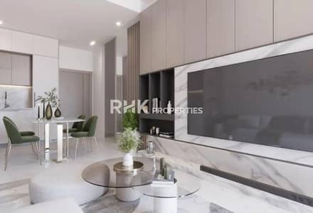 استوديو  للبيع في مجمع دبي لاند ريزيدنس (DLRC)، دبي - Contemporary living room with marble TV feature wall, built-in shelving, and open-plan kitchen in Dubai residential apartment