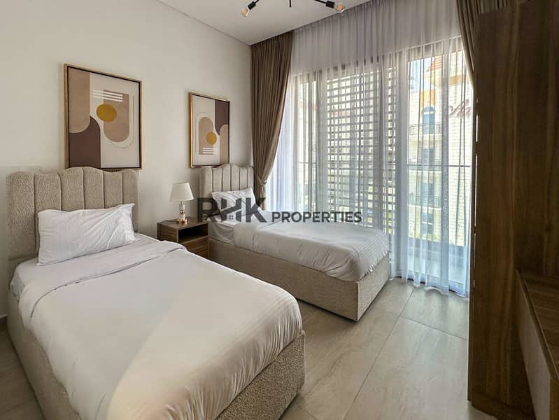 4 Twin bedroom with boucle beds, balcony access, and contemporary wall art in furnished JVC Dubai apartment