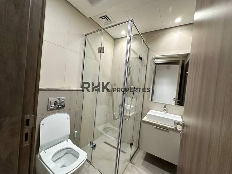 9 En-suite bathroom with glass shower enclosure, wall-hung toilet, and vessel sink in JVC Dubai apartment