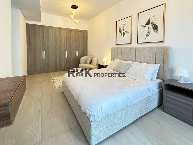 10 Spacious master bedroom with built-in wooden wardrobe and king bed in furnished Jumeirah Village Circle flat