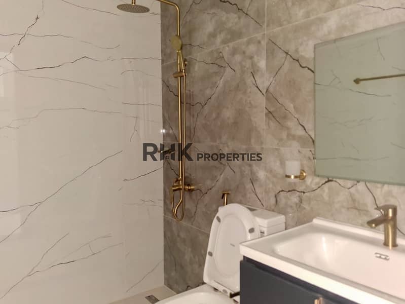 15 Second bathroom with grey marble wall tiles, gold shower column and wall-hung navy vanity