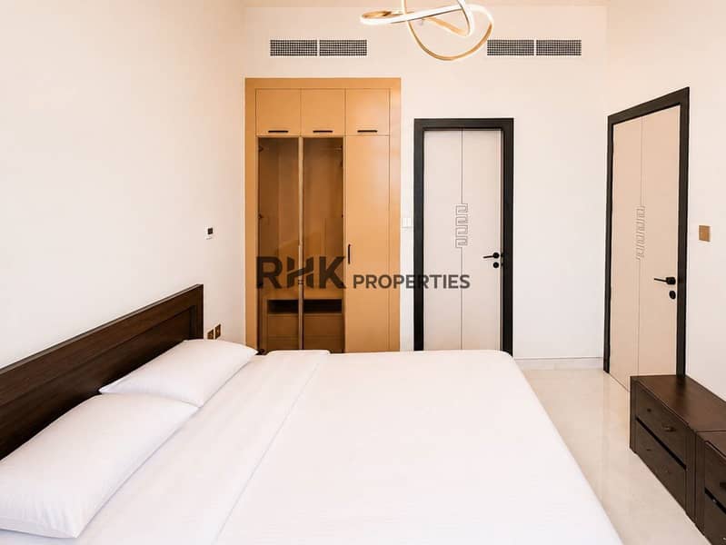 4 RHK Properties furnished bedroom with city view, dark wood furniture, and gold loop chandelier in Dubai