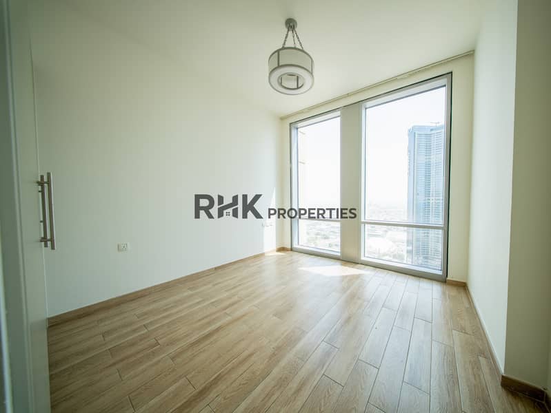 3 Bright bedroom with floor-to-ceiling windows and panoramic Dubai city view and wood-effect flooring