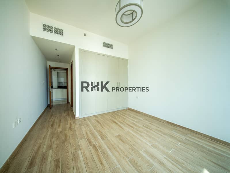 4 Spacious bedroom with built-in white wardrobes and wood-effect tile flooring in Dubai apartment