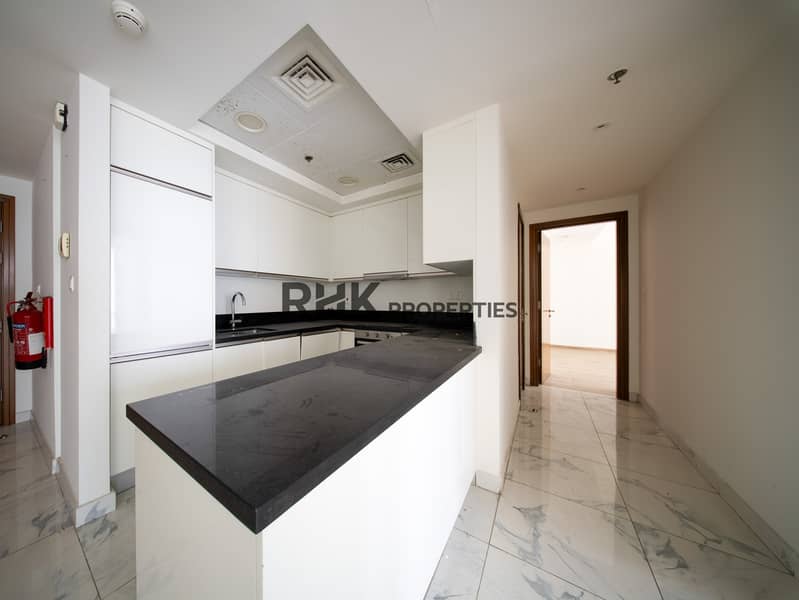 7 Modern open kitchen with black granite island, white gloss cabinets and marble flooring in Dubai apartment