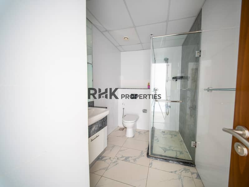 10 Modern bathroom with glass shower enclosure, marble flooring and dark granite vanity in Dubai apartment