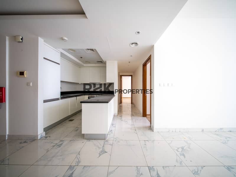 11 Fully fitted open-plan kitchen with black granite countertops and white cabinetry leading to living area
