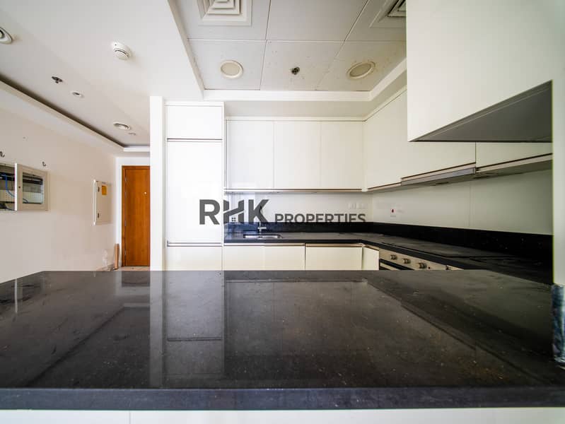 12 Polished black granite kitchen countertop with white gloss cabinetry and built-in oven in Dubai apartment