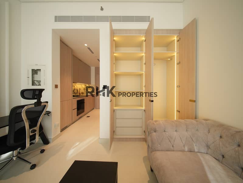 4 Built-in wardrobe with LED shelving, workspace and sofa in furnished Dubai studio apartment