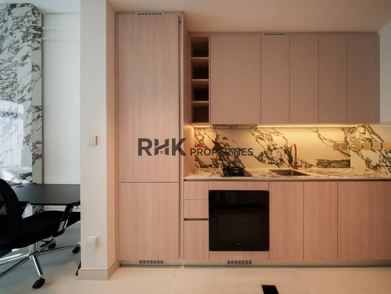8 Fitted kitchen with marble backsplash, oven and rose gold tap in modern Dubai studio Primary keyword: fitted kitchen Dubai studio