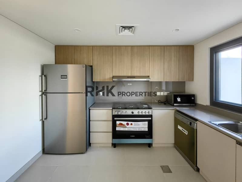 8 Fully fitted kitchen with stainless steel fridge, Bosch oven, wood cabinetry and microwave in Dubai community villa