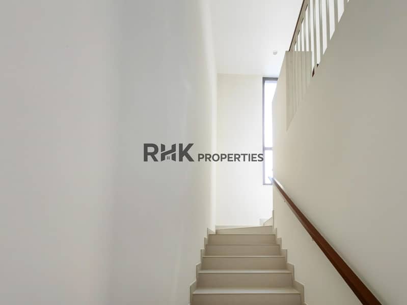 16 Light-filled staircase with wood handrail and high window in modern Dubai townhouse