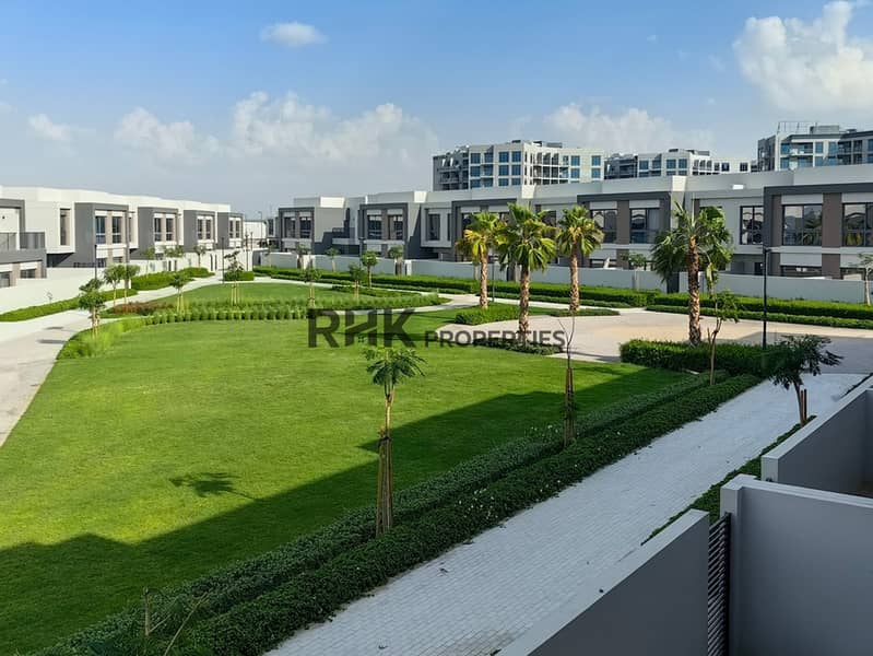2 Landscaped community park with lush green lawn, palm trees and modern townhouses in Dubai gated community