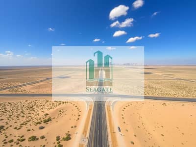 Земля промышленного назначения Продажа в Аль Джурф, Аджман - An_aerial_view_of_a_vast_barren_landscape_with_dry_sandy_land_and_sparse_vegetation. _The_scene_has_clear_blue_skies_and_a_few_scattered_clouds. _There_are_several_roads_intersecting_the_area_including_a_notable_wide_r. jpeg