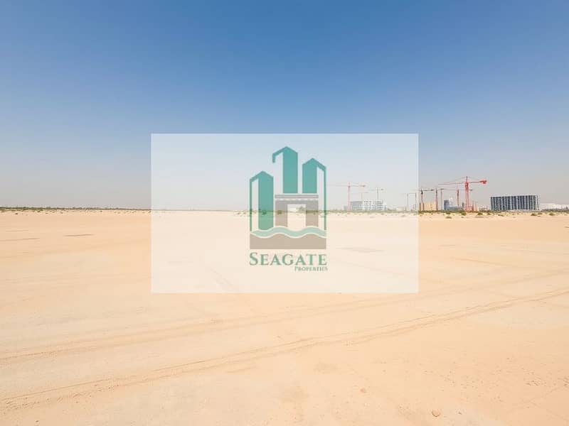 2 A_wide_angle_view_of_an_unoccupied_industrial_area_in_the_UAE_under_a_clear_blue_sky. _The_ground_is_a_smooth_sandy_surface_with_subtle_markings_indicating_future_development_plots. _In_the_distance_tall_cranes_and_unf. jpeg
