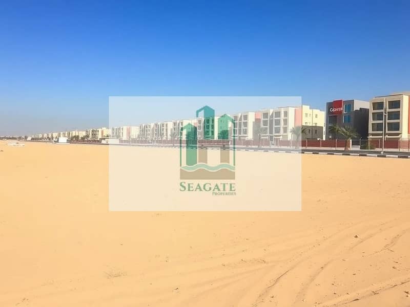 2 A_large_empty_residential_plot_in_the_UAE_situated_one_block_from_a_road. _The_scene_features_an_expansive_flat_sandy_terrain_without_trees_or_signs_providing_an_open_unobstructed_view. _The_sky_is_bright_blue_typical_. jpeg