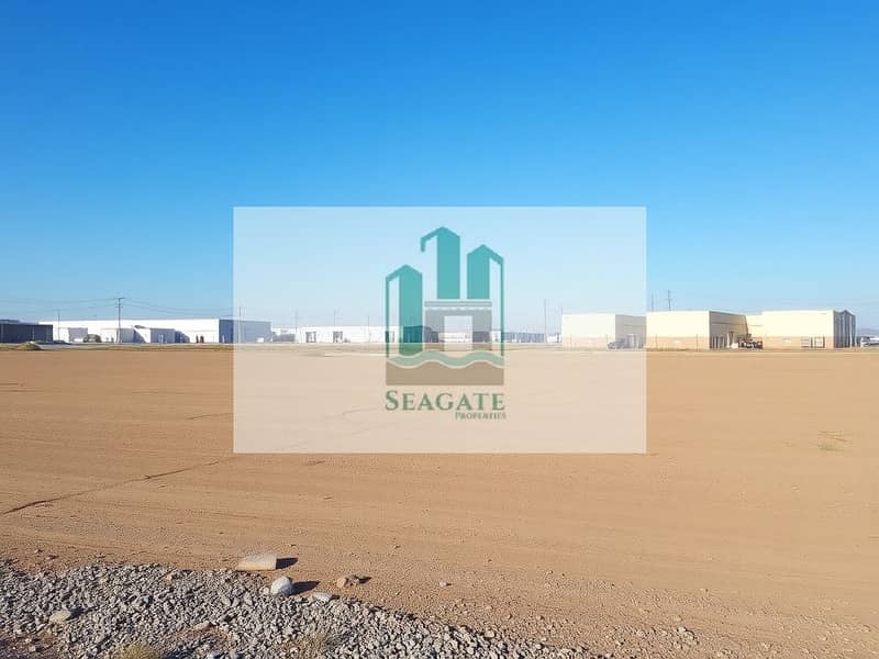2 A_vast_empty_industrial_plot_of_land_covered_with_dirt_and_gravel_ready_for_future_construction. _In_the_background_there_are_several_nearby_industrial_buildings_and_warehouses_under_a_clear_blue_sky. _Utility_poles_ca. jpeg