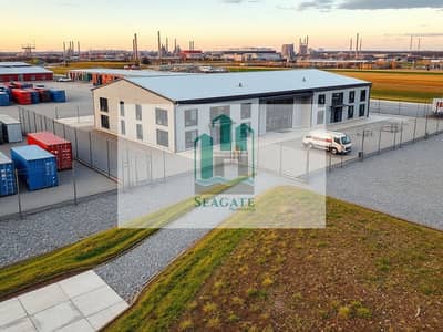 Трудовой лагерь в аренду в Аль Джурф, Аджман - An_exterior_view_of_a_staff_accommodation_building_situated_in_an_industrial_location. _The_structure_embodies_a_functional_and_modern_design_featuring_flat_roofs_and_large_windows. _Surrounding_the_building_are_fenced. jpeg