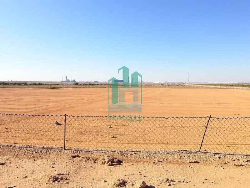 4 A_vast_empty_industrial_plot_with_flat_dry_land_under_a_clear_sky. _The_ground_is_a_mix_of_sandy_brown_and_clay_devoid_of_any_vegetation_or_structures. _A_simple_chain_link_fence_surrounds_the_perimeter_emphasizing_the. jpeg