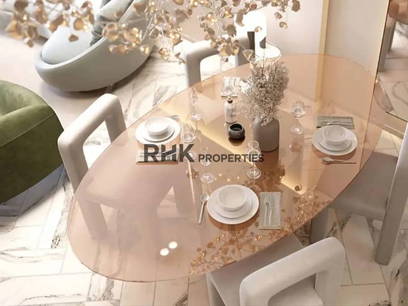 5 Oval amber glass dining table with white sculptural chairs and gold leaf chandelier in luxury Dubai apartment