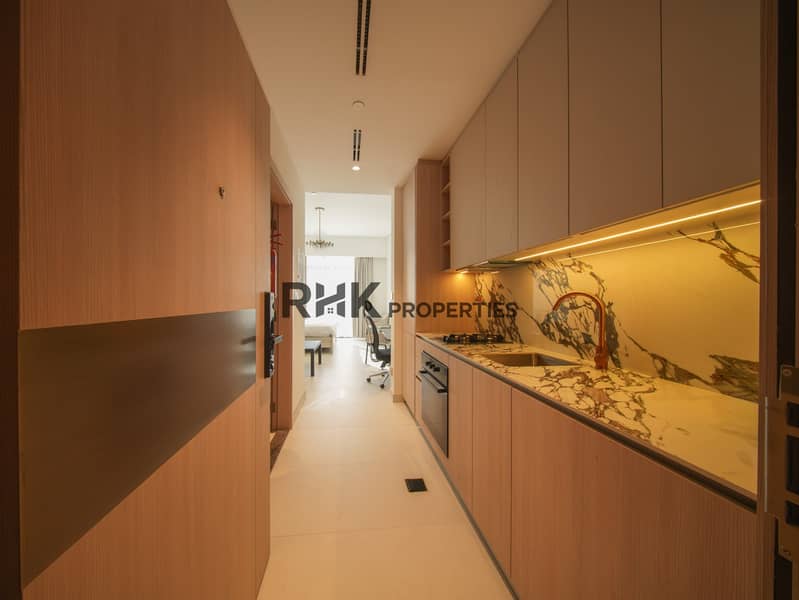 6 Luxury studio apartment kitchen with marble countertops, built-in cooktop, oven, and designer cabinetry