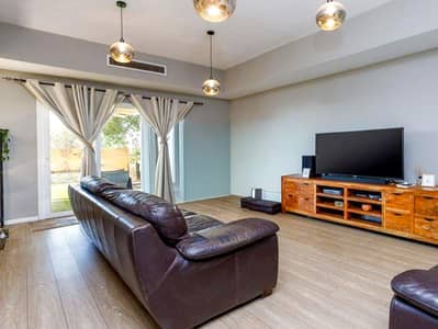 2 habitaciones Villa para en Venta en Arabian Ranches, Dubai - Spacious living room with dark leather sofa, large TV, and garden sliding door