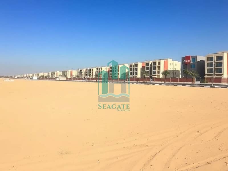 3 A_large_empty_residential_plot_in_the_UAE_situated_one_block_from_a_road. _The_scene_features_an_expansive_flat_sandy_terrain_without_trees_or_signs_providing_an_open_unobstructed_view. _The_sky_is_bright_blue_typical_. jpeg