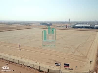 Industrial Land in vendita a Al Sajaa, Sharjah - A_large_empty_industrial_plot_of_land_in_Dubai_featuring_extensive_flat_terrain_with_clear_demarcations_for_potential_development. _The_scene_includes_perimeter_fencing_and_signs_indicating_the_land_is_for_sale_or_lea. jpeg