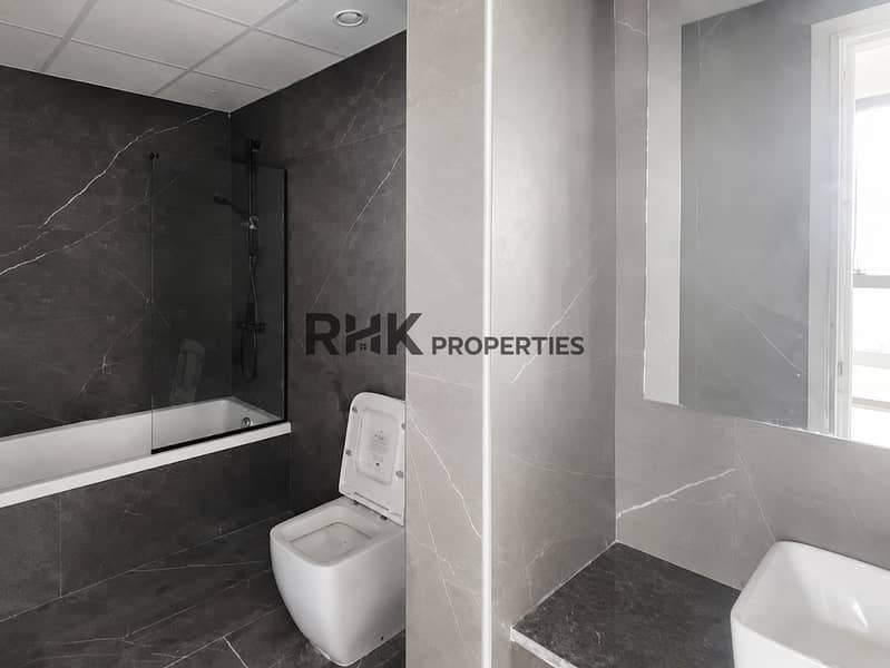 8 Noor 5 apartment bathroom with bathtub, glass screen and dark wall tiles