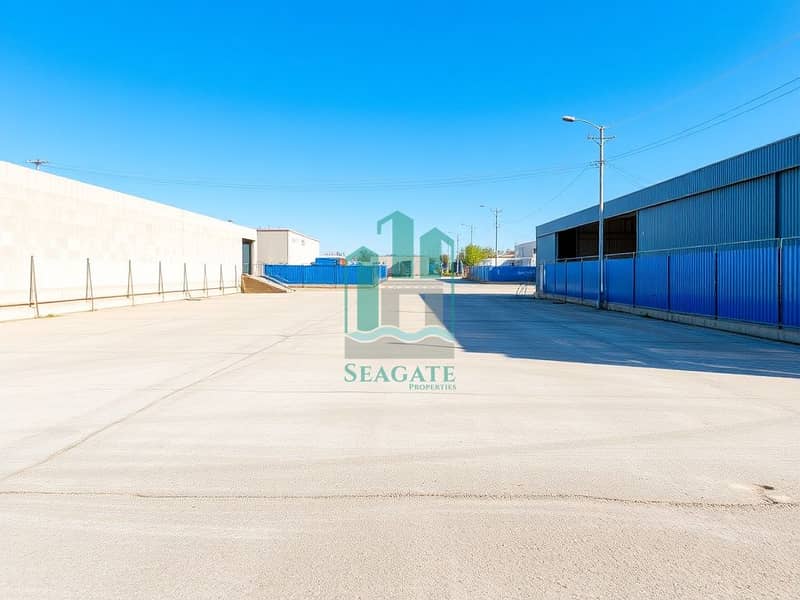 2 A_large_industrial_yard_with_an_expanded_empty_ground_area_clearly_visible_and_adjacent_to_a_busy_road. _The_yard_features_a_bare_ground_surface_lined_with_sturdy_concrete_walls_on_three_sides_and_a_blue_corrugated_me. jpeg