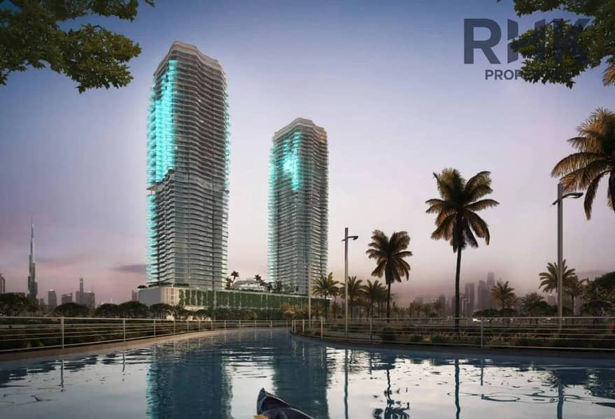3 Twin residential towers lit at night with Dubai city skyline and fireworks