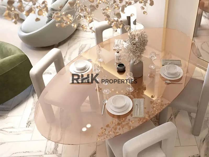 4 Oval amber glass dining table with white sculptural chairs and gold leaf chandelier in luxury Dubai apartment