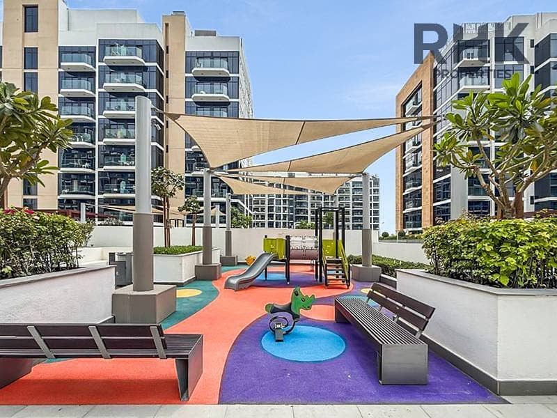 7 Shaded children's playground with slide and seating at Azizi Riviera family community, Dubai