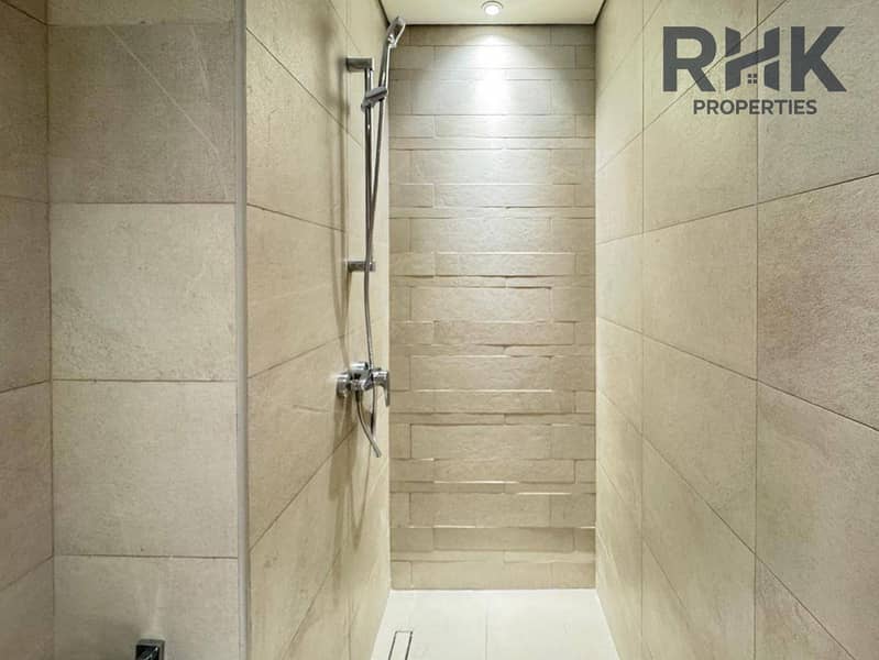9 Walk-in shower with stone-effect tiling and rainfall fixtures in a Dubai apartment bathroom