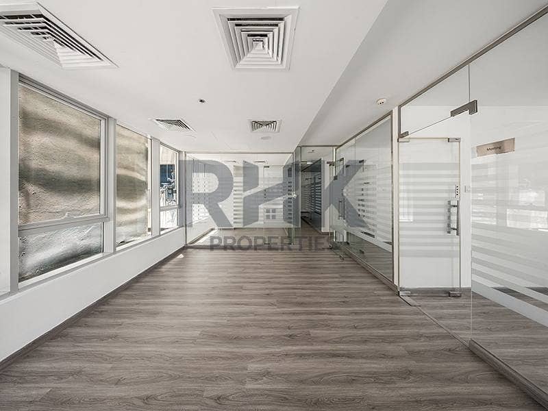 2 Partitioned office in Ontario Tower Business Bay featuring a meeting room, natural light and laminate flooring along a glass-walled corridor